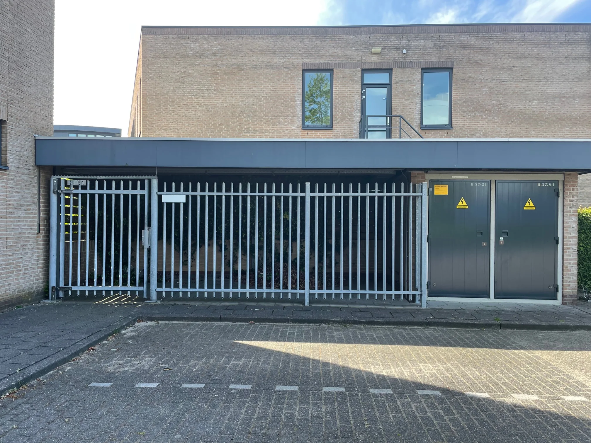 Stalen toegangshek en elektrische deuren bij een gebouw aan de Rivium 4e Straat.